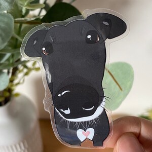 May include: A black and white cartoon dog sticker with a pink heart on its chest. The dog has a white collar and is looking at the camera.