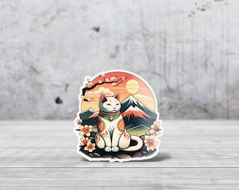 May include: A white Japanese Maneki-Neko lucky cat with a red collar and gold bell sitting on a rock with a mountain and cherry blossom tree in the background. The background is a sunset with a red, orange, and yellow sky.