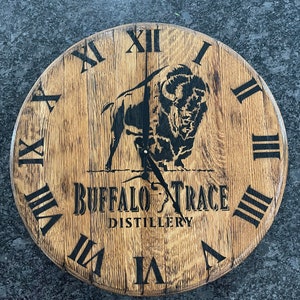May include: A wooden clock face with Roman numerals and a black silhouette of a buffalo. The clock face is inscribed with "Buffalo Trace Distillery".