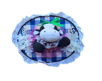 Mucca di campagna con fiocco verde e sfondo a quadretti blu e bianchi con fiori, peluche tassidermizzato