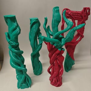 May include: Four abstract sculptures in shades of green and red. The forms resemble intertwined vines or branches, with smooth, glossy surfaces. The sculptures are arranged in a row, with varying heights and intricate details.