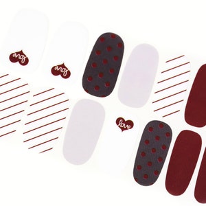 May include: Nail polish strips with various designs, including red stripes, white polka dots, and solid red. The strips also feature the word "love" in a heart shape.