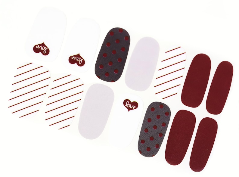 May include: Nail polish strips with various designs, including red stripes, white polka dots, and solid red. The strips also feature the word "love" in a heart shape.