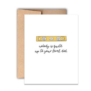 May include: A white greeting card with a brown envelope featuring a yellow spirit level illustration and the black text: nobody is quite up to your level, dad. The card has a clean design with a simple line drawing of a construction tool.