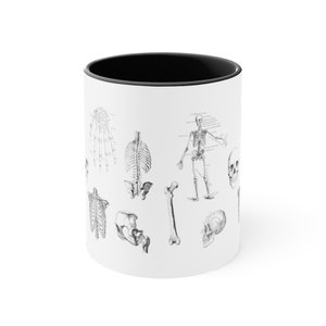 May include: White ceramic mug with a black interior featuring a black and white illustration of a human skeleton with various bones and a skull.