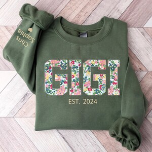 May include: A green sweatshirt with the word "GIGI" in floral print and the text "EST. 2024" below it.