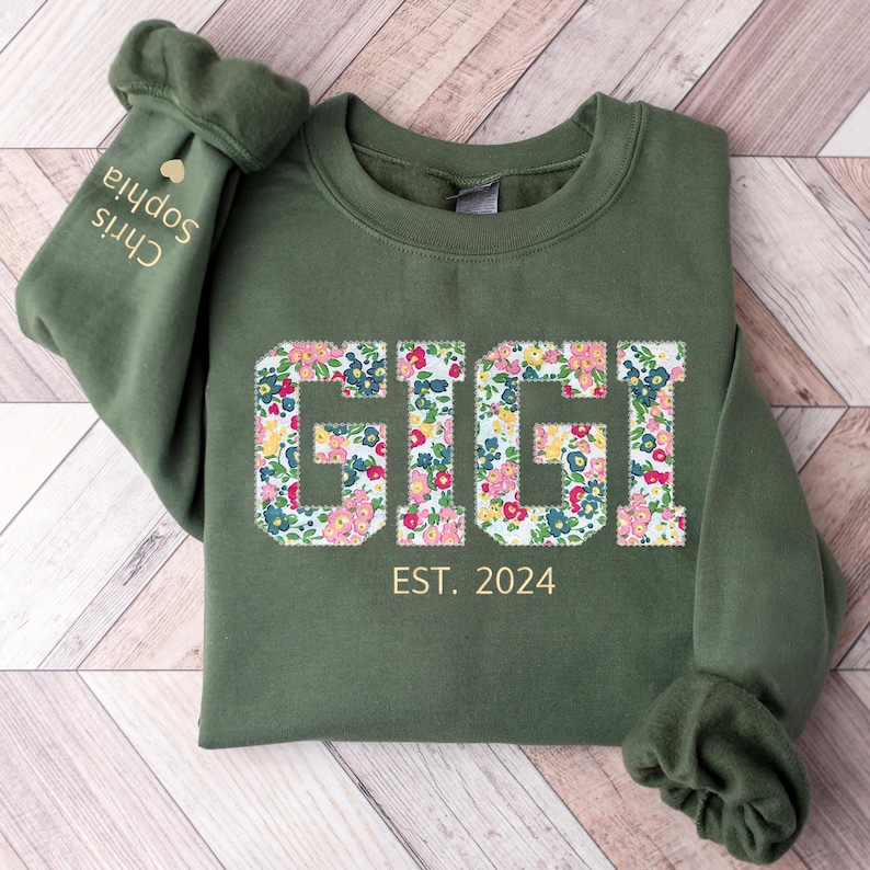 May include: A green sweatshirt with the word "GIGI" in floral print and the text "EST. 2024" below it.