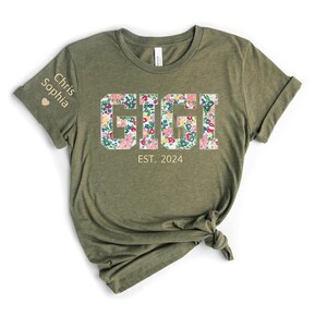 May include: A green t-shirt with a floral print that says "GIGI EST. 2024". The left sleeve has the names "Chris Sophia" and a heart.