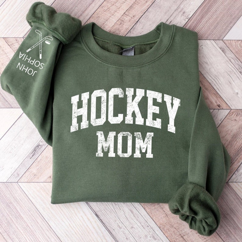 May include: A green sweatshirt with the text "HOCKEY MOM" in white distressed lettering.