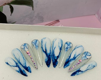 May include: Set of ten blue and white marble-effect stiletto false nails with silver glitter accents and rhinestones.