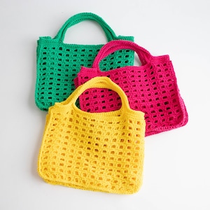 May include: Three crocheted tote bags in different colors: green, pink, and yellow. The bags are made with a simple grid pattern and have a single handle.