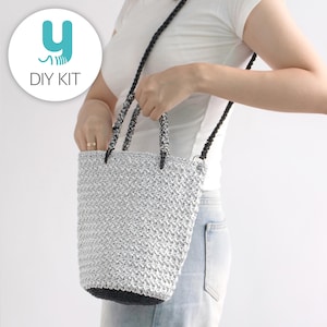 May include: A silver crocheted bucket bag with a black base and handles. The bag has a black and silver strap for shoulder or crossbody wear. The image includes a logo that says "DIY KIT".