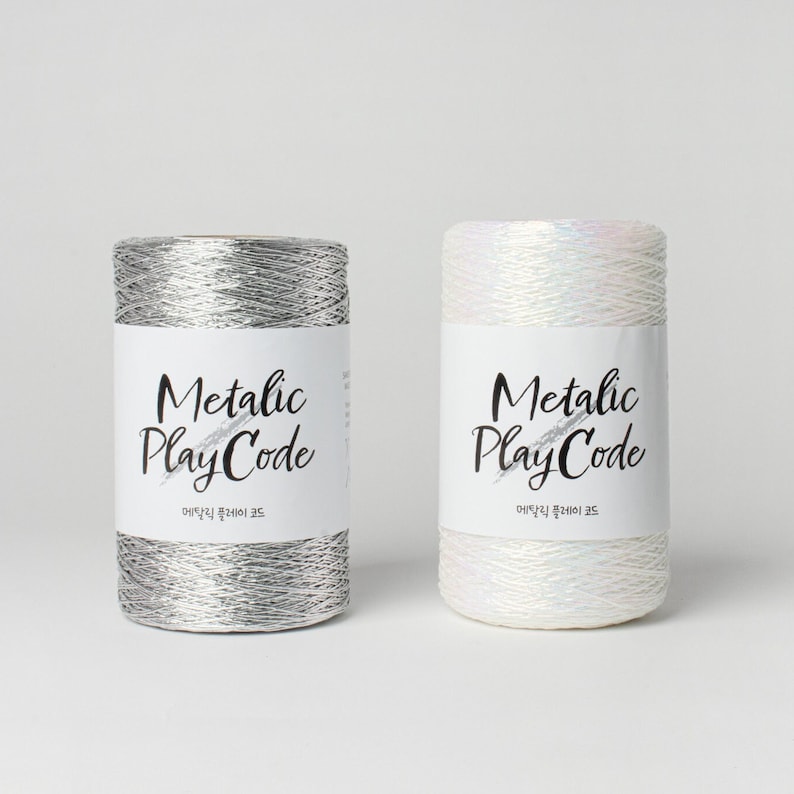May include: Two spools of metallic yarn, one silver and one white, with the text "Metallic PlayCode" on each label.