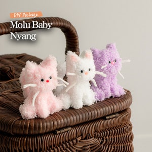 Może przedstawiać: Trzy pluszowe zabawki w kształcie kota w wiklinowym koszu. Koty są różowe, białe i fioletowe. Tekst "DIY Package Molu Baby Nyang" jest widoczny w lewym górnym rogu obrazu.