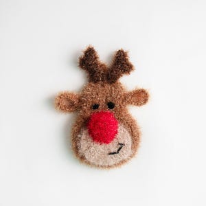 May include: A brown and beige knitted reindeer ornament with a red nose and black eyes.