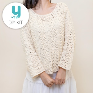 Könnte beinhalten: Cremefarbener Häkelpullover mit Rundhalsausschnitt und langen Ärmeln. Der Pullover hat ein detailliertes Lochmuster. Ein weißer Kreis mit dem Text "y DIY KIT" befindet sich in der oberen linken Ecke. Der Pullover ist ein DIY-Kit.