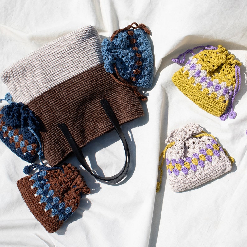 May include: A set of four crocheted bags in various colors and patterns. The bags are made with a combination of brown, white, blue, yellow, and purple yarn. The bags are all different sizes and shapes, and they are perfect for carrying small items.