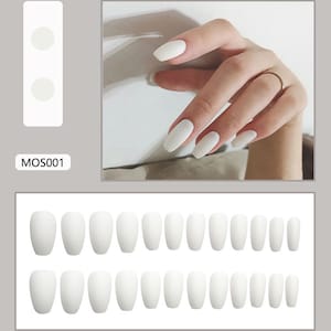 Könnte beinhalten: Ein Set weißer, mattierter Kunstnägel in verschiedenen Größen. Das Bild zeigt auch eine Hand mit dem gleichen Nagelstil und den Text "MOS001".