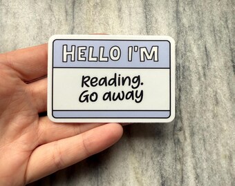 May include: White sticker with a blue border and the text "HELLO I'M Reading. Go away" in black.