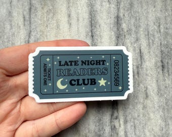 May include: A gray and white sticker shaped like a ticket stub with the text "Late Night Readers Club" and a crescent moon and star. The ticket number is 08234569.