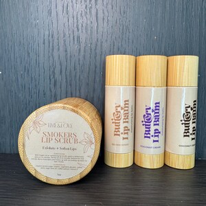 Puede incluir: Un conjunto de tres b&aacute;lsamos labiales en tubos de madera con el texto "Buttery Lip Balm" y los sabores "Brown Sugar", "Coconut Cream" y "Coconut Cream".  Tambi&eacute;n se muestra un tarro de exfoliante labial con el texto "Smokers Lip Scrub" y las palabras "Exfoliate + Soften Lips".