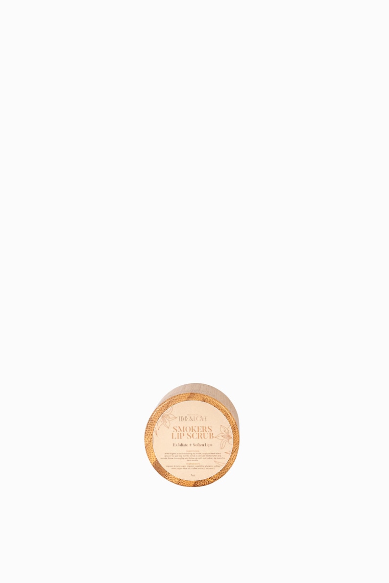 Puede incluir: Un tarro redondo de madera con tapa dorada que contiene un exfoliante labial. El tarro est&aacute; etiquetado con "Smokers Lip Scrub" y "Exfoliate + Soften Lips".
