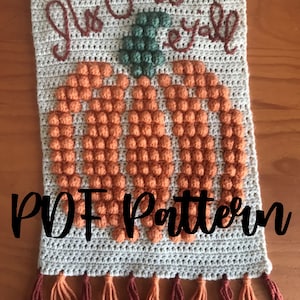Peut inclure: Modèle de crochet pour une citrouille avec le texte "It's Fall Y'all" en fil brun. La citrouille est faite de fil orange et a une tige verte. Le modèle comprend une frange en bas.