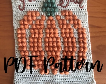 May include: Crochet pattern for a pumpkin with the text "It's Fall Y'all" in brown yarn. The pumpkin is made with orange yarn and has a green stem. The pattern includes a fringe at the bottom.