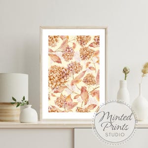 Puede incluir: Impresión floral enmarcada con un diseño de acuarela de hortensias y hojas en tonos melocotón, beige y crema. La obra de arte se exhibe sobre una superficie blanca con una lámpara y jarrones. La impresión es de Minted Prints Studio.