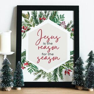 Peut inclure: Une impression encadrée avec une illustration aquarelle de branches de conifères et de baies rouges. L'impression présente le texte "Jésus est la raison de la saison" dans un hexagone blanc.