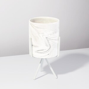 May include: White ceramic planter with a marble pattern on a white metal tripod stand.