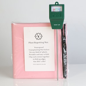 May include: A pink plant repotting mat with a green moisture meter. The mat is waterproof, portable, and easy to fold, measuring 39.4 x 39.4 inches. The moisture meter displays a moisture level.