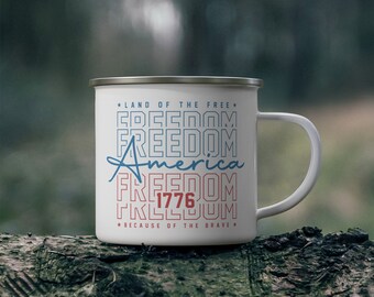 May include: White enamel camping mug with a red, white, and blue graphic that says "Land of the Free", "Freedom", "America", "Freedom", "1776", and "Because of the Brave".