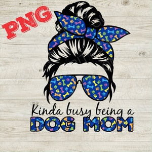 May include: A black and white illustration of a woman with a messy bun wearing sunglasses and a blue bandana with paw prints and bones. The text "Kinda busy being a DOG MOM" is below the illustration.