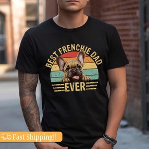 May include: Black t-shirt with a vintage-style graphic of a French Bulldog peeking over a sunset. The text reads "Best Frenchie Dad Ever".