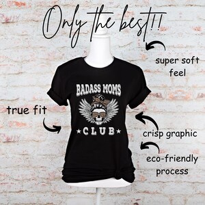 May include: Black t-shirt with a white graphic of a skull wearing sunglasses and a bandana with the text "BADASS MOMS *CLUB*" printed on it.
