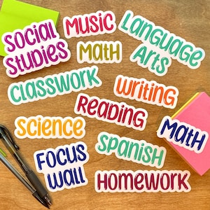 May include: A collection of die-cut stickers featuring school subject labels including Social Studies, Music, Math, Language Arts, Classwork, Writing, Reading, Science, Spanish, Focus Wall, and Homework in various colors with white borders.