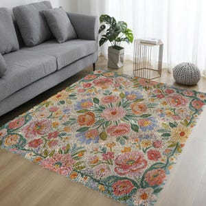 May include: A rectangular rug with a floral design. The rug features a cream-colored background with a pattern of pink, orange, yellow, and blue flowers. Green leaves and stems surround the flowers. The rug is placed on a wooden floor.