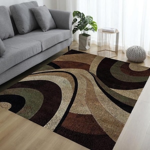 May include: A rectangular area rug with a swirling pattern in shades of brown, beige, and black. The rug features a textured surface and is placed on a light-colored wooden floor. The design creates a sense of movement and adds visual interest to the room.