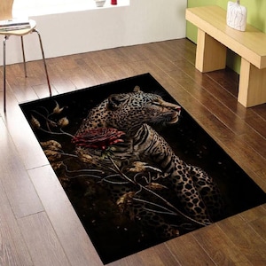 Op de afbeelding: Rechthoekig vloerkleed met een gedetailleerde illustratie van een luipaard en een rode roos. Het luipaard heeft een gevlekte vacht tegen een donkere achtergrond. Het vloerkleed is ontworpen voor gebruik binnenshuis.