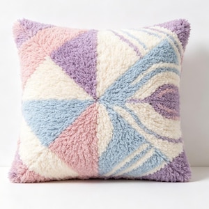 May include: Square decorative pillow with a geometric design. The pillow features a soft, textured fabric in pastel colors: pink, lavender, light blue, and cream. The design is a series of triangles and curved lines radiating from the center.