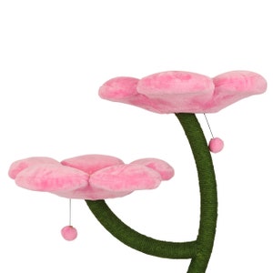 May include: Pink cat tree with two flower-shaped platforms and a green sisal-covered post. The platforms are made of soft plush and have a dangling toy.