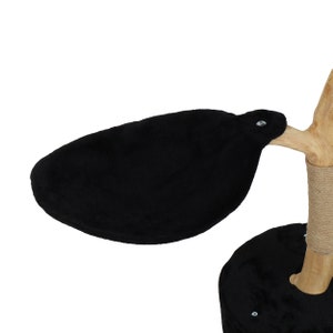 May include: A black cat tree platform with a soft, plush surface. The platform is attached to a wooden branch with a rope-covered base.