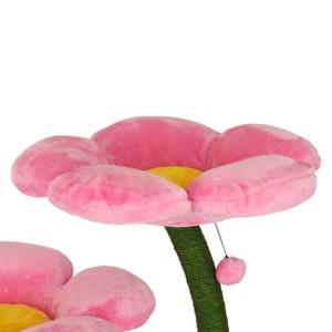 May include: Pink cat scratching post shaped like a flower with a yellow center. The post is covered in sisal rope and has a dangling toy.