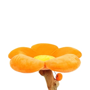 May include: Orange flower-shaped cat bed with a yellow center and a dangling orange toy. The bed is attached to a wooden base.