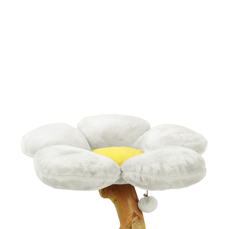 May include: A white plush cat bed shaped like a daisy with a yellow center. The bed is attached to a wooden base with a dangling gray pom-pom.