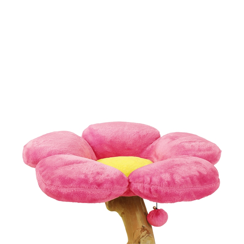 May include: Pink flower-shaped cat bed with a yellow center, attached to a wooden post with a pink pom-pom.
