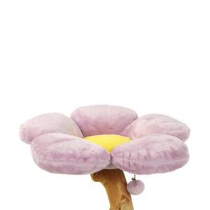 May include: A purple flower-shaped cat bed with a yellow center, attached to a wooden post with a dangling fuzzy toy.