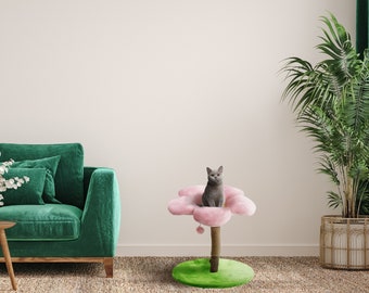 May include: A pink flower-shaped cat scratching post with a grey cat sitting on the top platform. The post is on a green base and has a brown sisal rope for scratching.