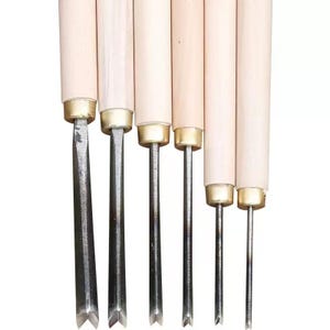 May include: A collection of six wood carving tools. Each tool features a light-coloured wooden handle and a metal blade. The blades have different profiles, including V-shaped and straight edges. These tools are designed for detailed woodworking and carving.